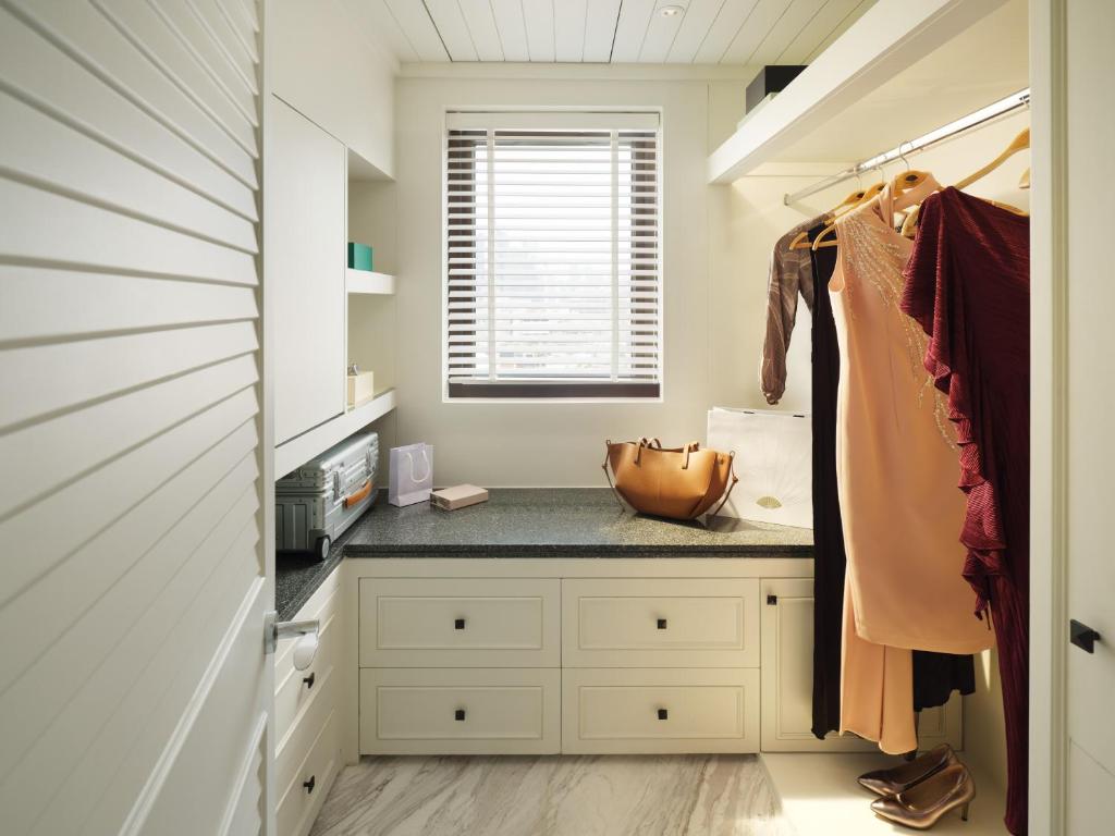 A dressing area combining an open wardrobe, drawers and a window-side counter.