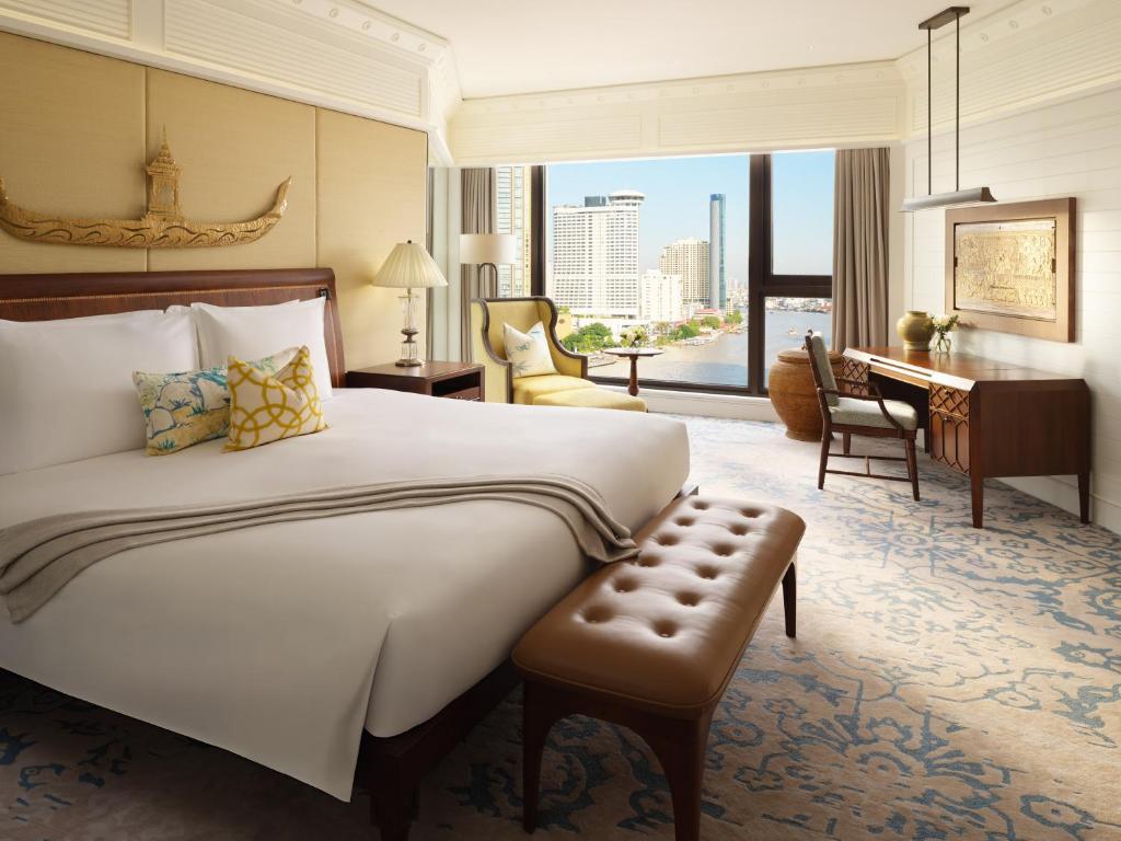 A bedroom with a large bed, window-side seating and a dedicated writing desk.