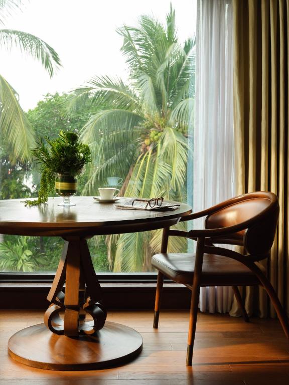 A small writing table beside a window overlooking palms.