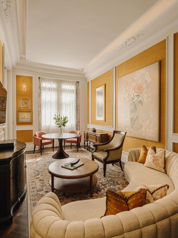 A richly decorated sitting room with a curved sofa, coffee table, and small dining nook.