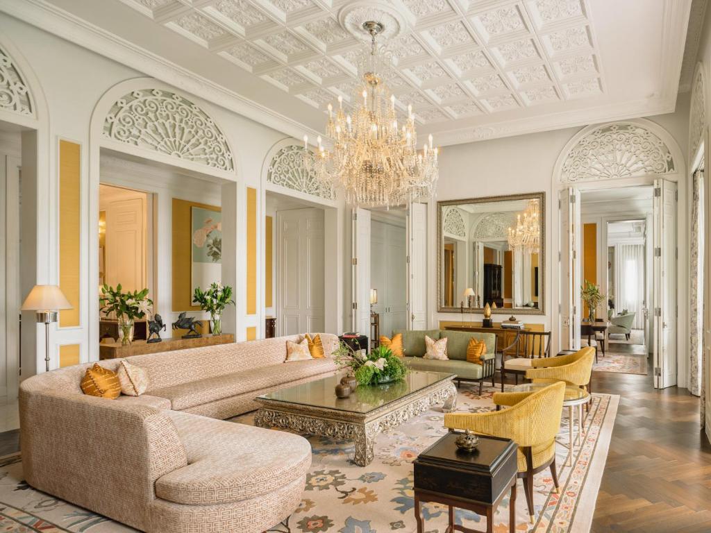 A grand salon with a sweeping sofa, crystal chandelier, and ornate architectural details.