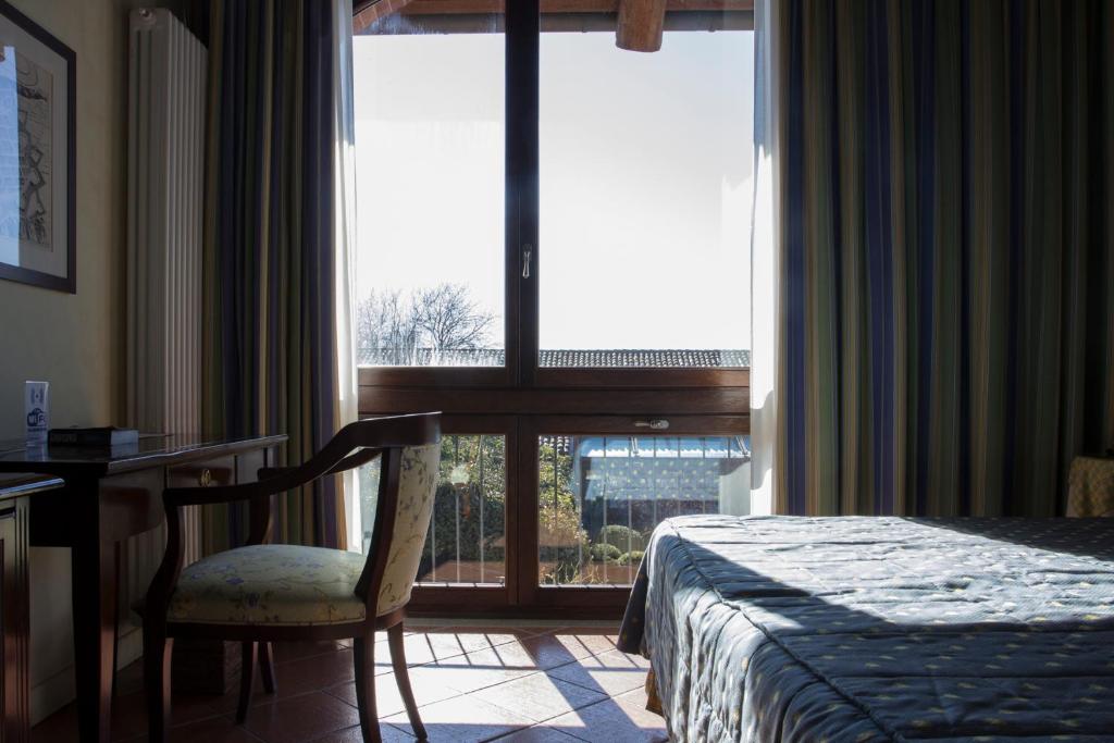 a bedroom with a bed and a desk and a window at Tenuta La Cascinetta in Buriasco