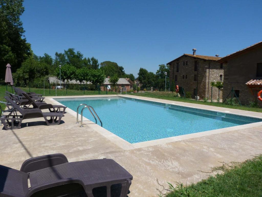 a swimming pool in a yard with chairs and a table at Mas El Ferrés in Joanetes