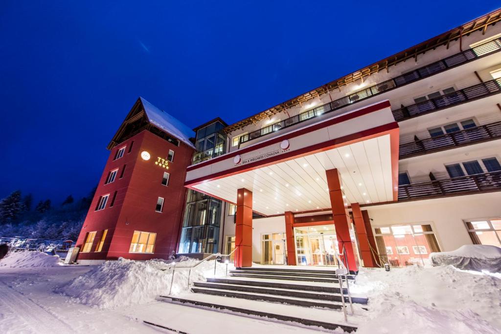 um edifício com degraus cobertos de neve à sua frente em Hotel TTS**** Spa&Wellness Covasna em Covasna