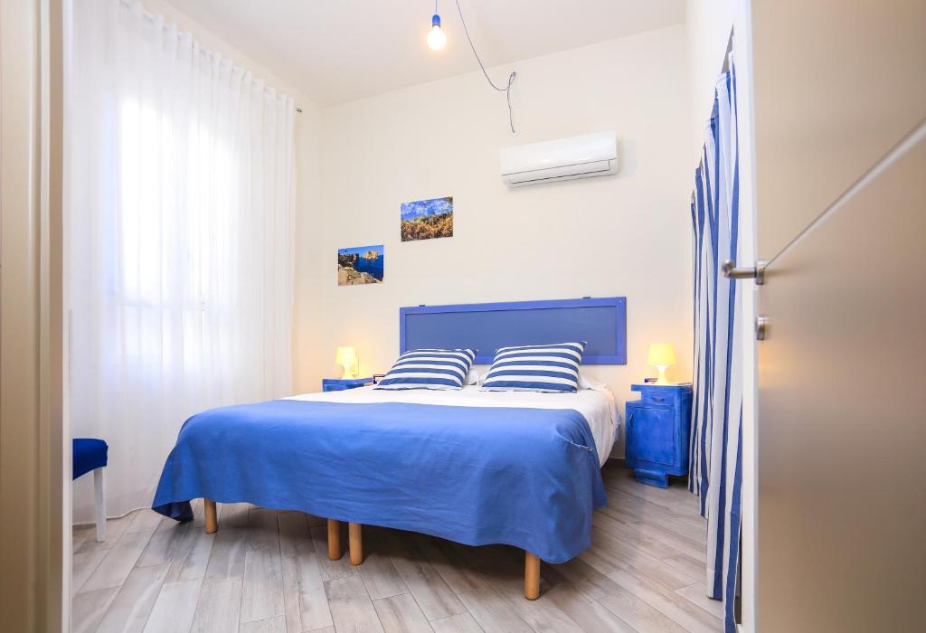 sypialnia z dużym łóżkiem z niebieską pościelą i poduszkami w obiekcie La Posidonia Oceanica w mieście Alghero