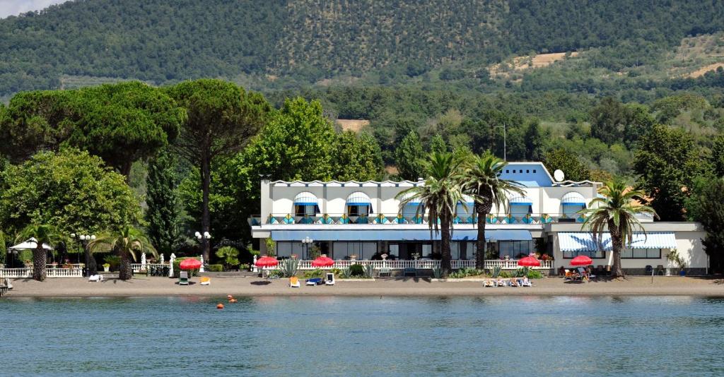 - un bâtiment sur une plage à côté d'une étendue d'eau dans l'établissement Hotel Lido - Beach and Palace, à Bolsena