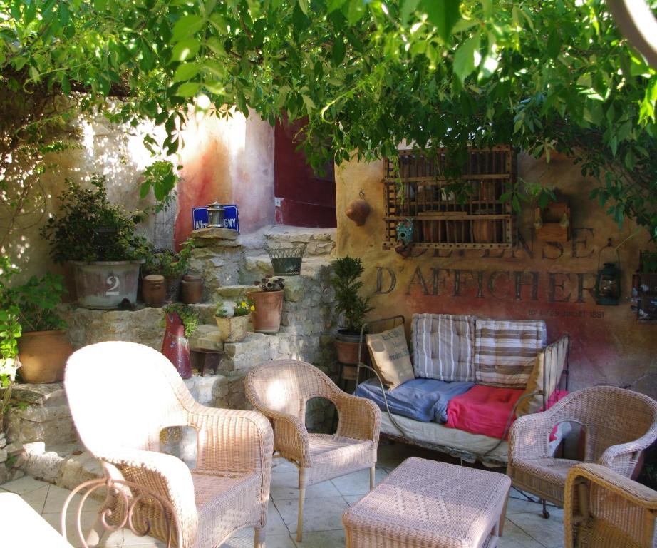ヴェゾン・ラ・ロメーヌにあるChambre d'hôtes Au coquin de sortの木の下にソファと椅子が備わるパティオ