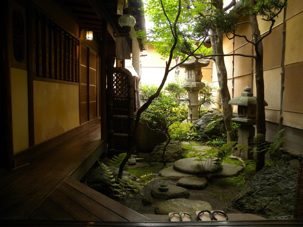 an asian garden with sandals in front of a building at Guest House Kingyoya in Kyoto