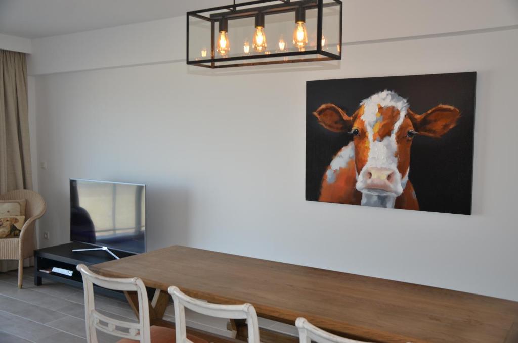 een tafel met een foto van een koe aan de muur bij Apartment Beach in Blankenberge