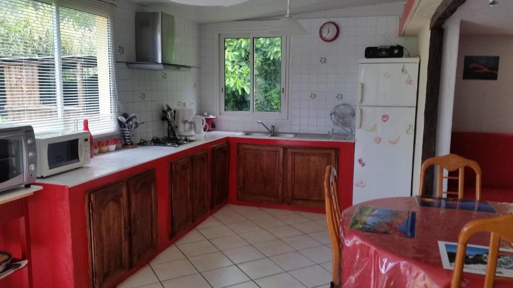 een keuken met rode kasten en een witte koelkast bij Les Lierrres in Cilaos