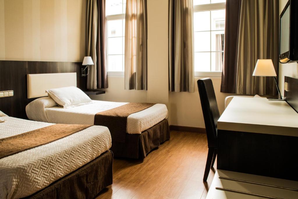 Habitación de hotel con 2 camas y escritorio en Hospedium Hotel Triana en Miajadas