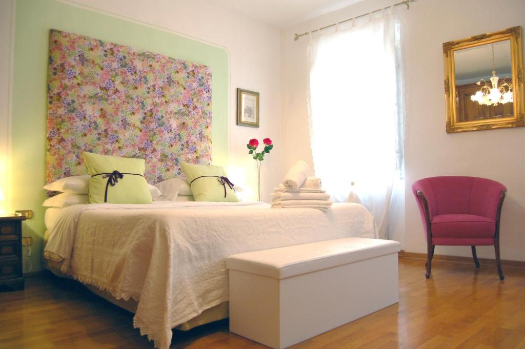 sypialnia z białym łóżkiem z zagłówkiem kwiatowym w obiekcie Casa del Bernini w mieście San Quirico dʼOrcia