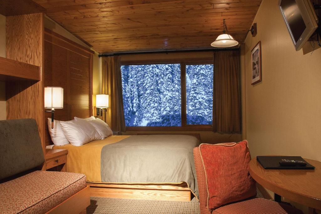 een slaapkamer met een bed en een groot raam bij Sunshine Mountain Lodge in Banff