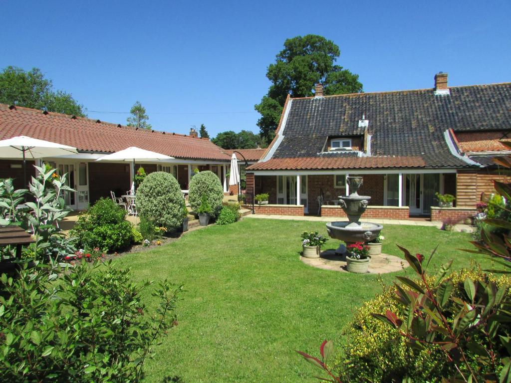 a yard with a fountain in front of a house at Decoy Barn Fritton in Fritton