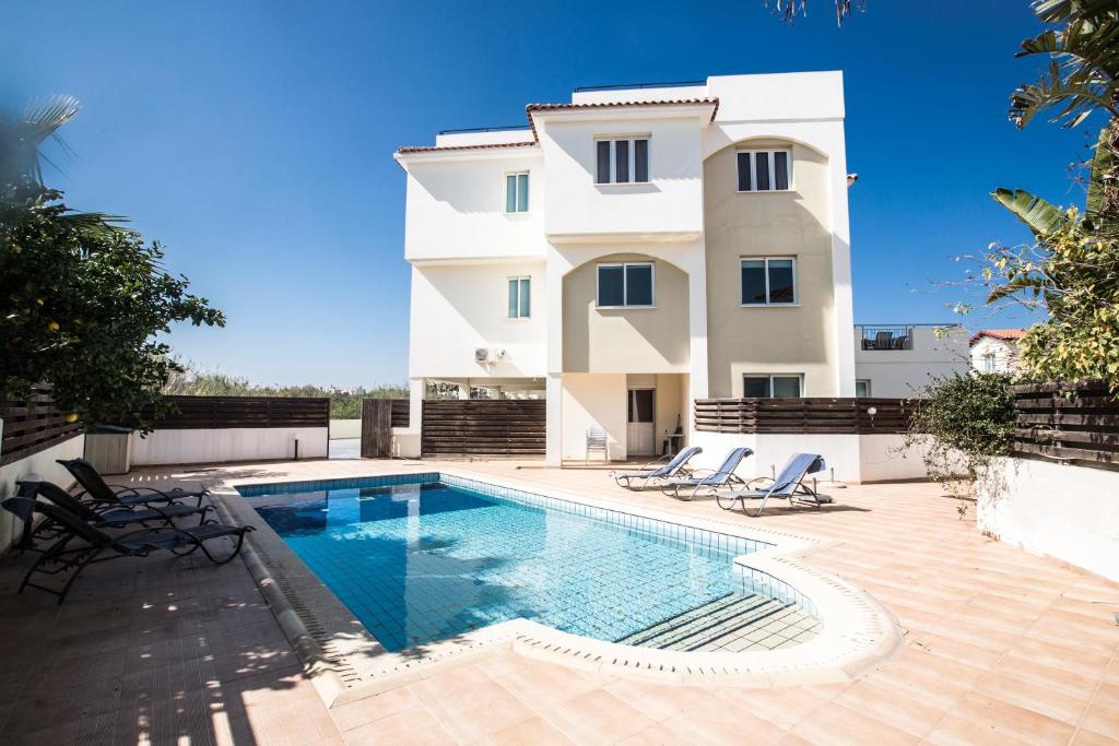 a villa with a swimming pool in front of a building at Orestiada Apartments in Protaras