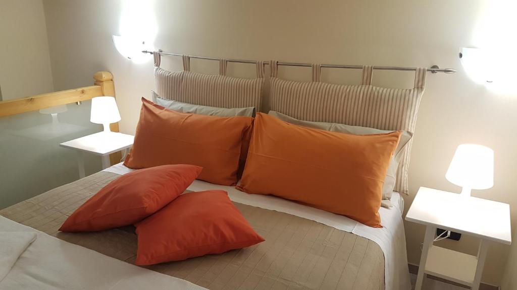 ein Bett mit orangefarbenen und grauen Kissen darauf in der Unterkunft Loft al Vicoletto sul Mare in Letojanni