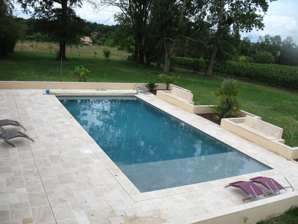 a swimming pool with two chairs in a yard at Gite Le Chardon Fleuri in Teuillac