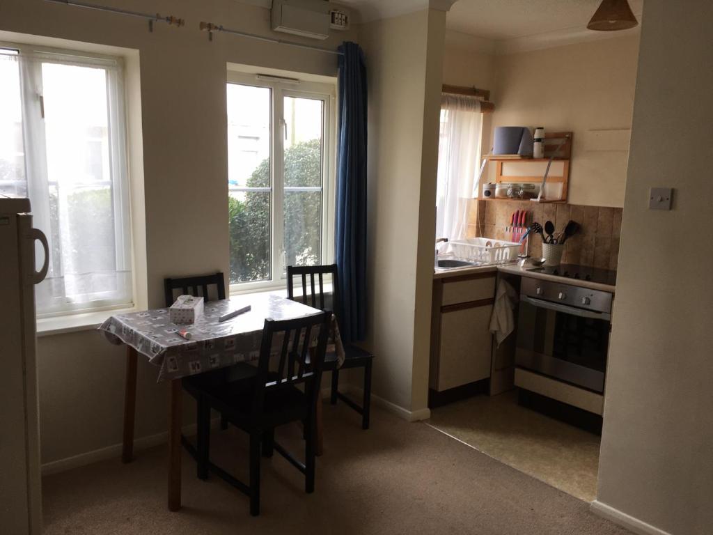 a kitchen with a table and chairs and a table and window at Grace's HQ in Aldershot