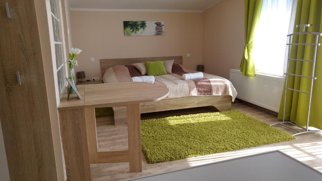 een slaapkamer met een bed en een tafel met een groen tapijt bij Bundics Vendégházak in Lenti