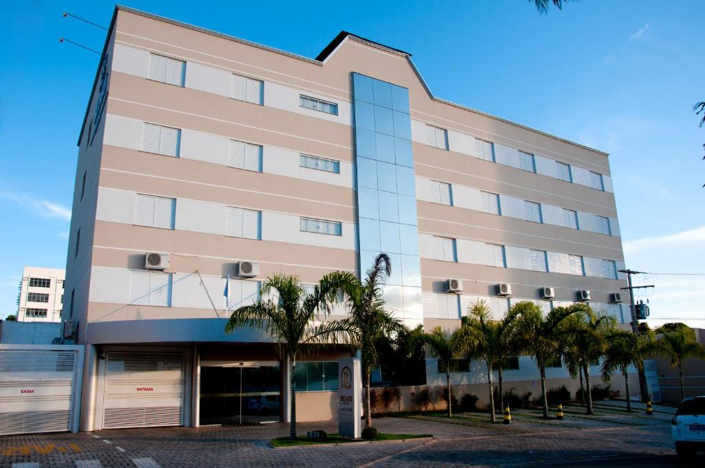 a tall building with palm trees in front of it at Hotel Roari in Cuiabá