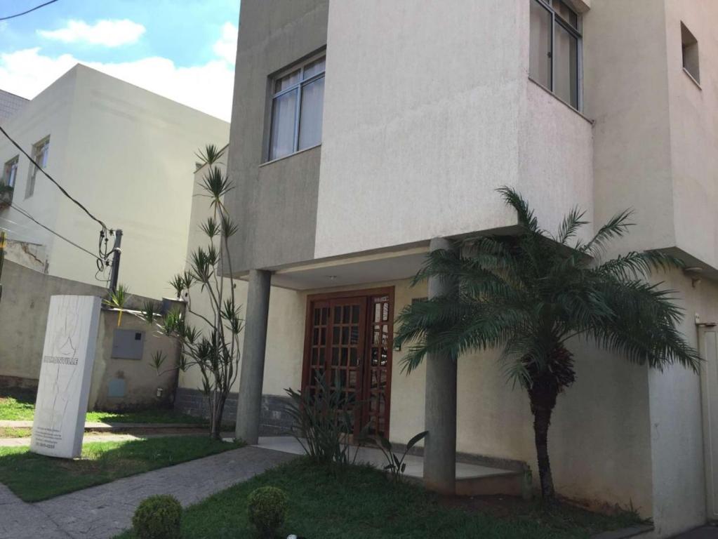 a house with a palm tree in front of it at Hospedagem Chamonville in Belo Horizonte