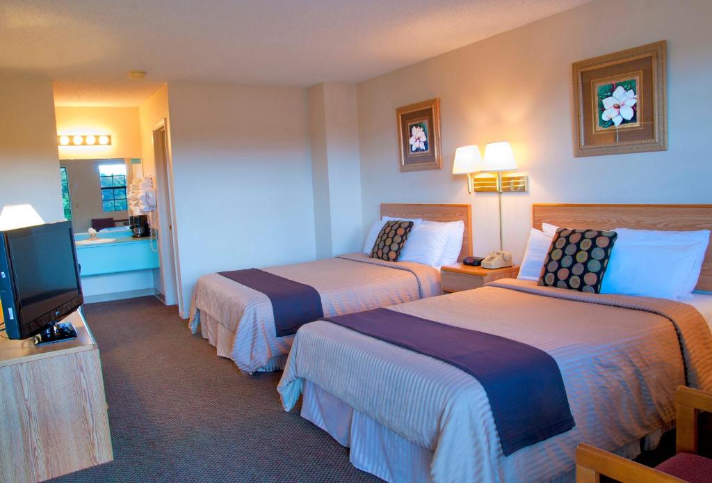 a hotel room with two beds and a flat screen tv at Regency Inn Eureka Springs in Eureka Springs