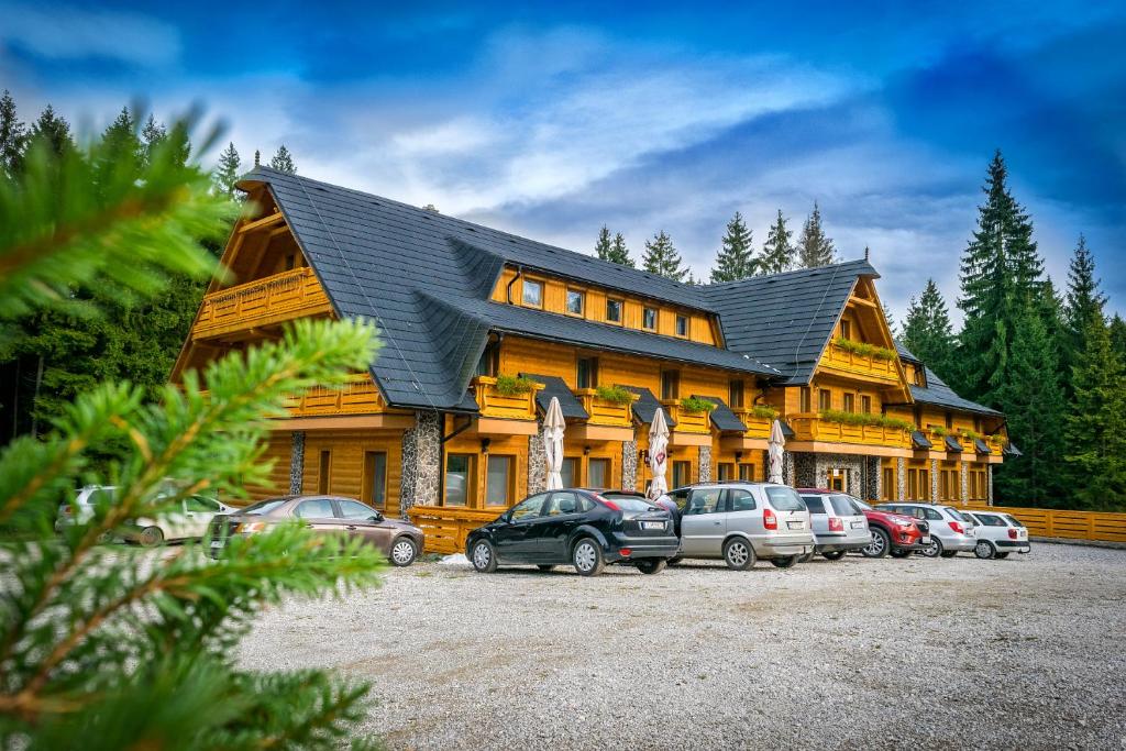 a large house with cars parked in front of it at Horský Hotel Kristína in Hruštín