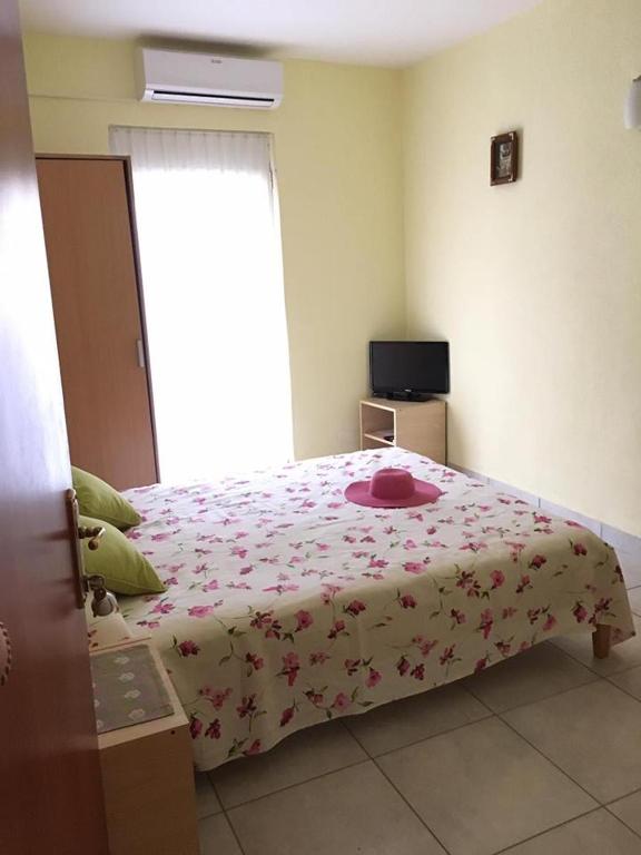 a bedroom with a bed with a flowered blanket and a window at Apartments Villa Dadora in Sutomore