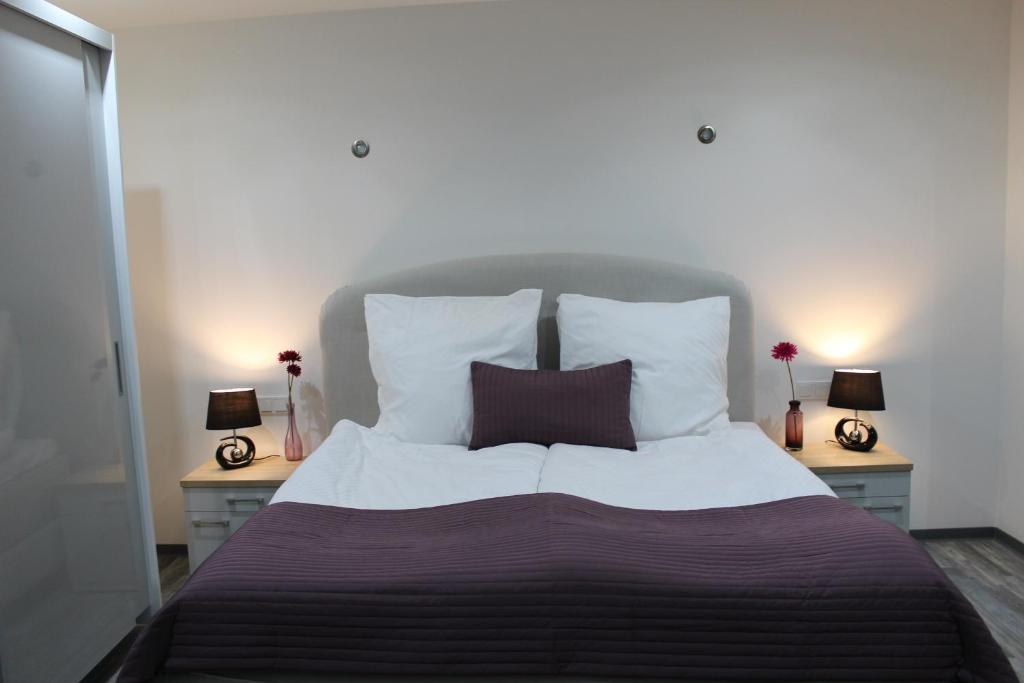a bedroom with a large bed with pillows and two lamps at Pension am Stummplatz in Neunkirchen