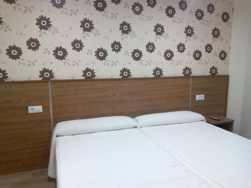 een slaapkamer met een wit bed en een houten hoofdeinde bij Pensión Costiña in Noya