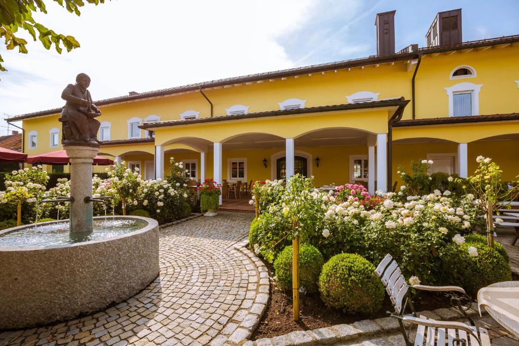 a statue in front of a yellow house with a fountain at Hotel Kandler in Notzing