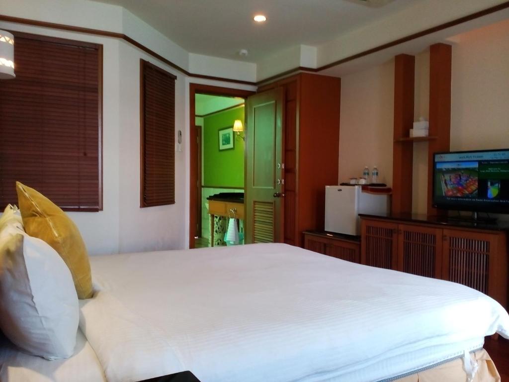 a bedroom with a large white bed and a television at Wonderland Private Chalet at Port Dickson in Port Dickson