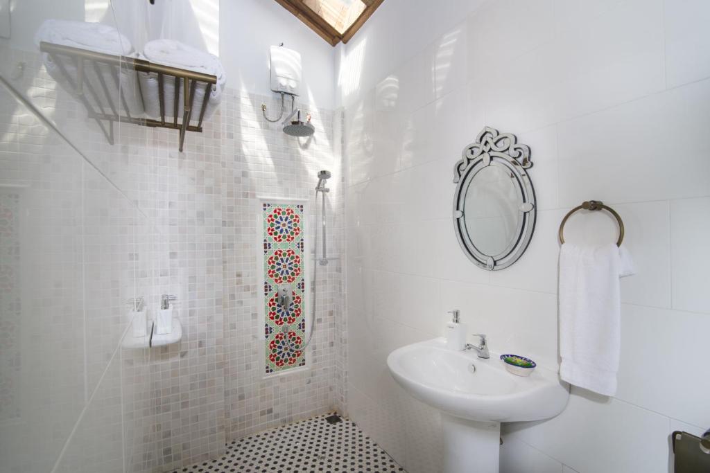 a white bathroom with a sink and a mirror at Jawi Peranakan Mansion in George Town
