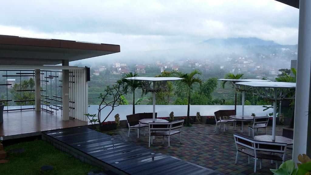 patio ze stołami i krzesłami oraz widokiem na miasto w obiekcie Moscato Hotel w mieście Lembang