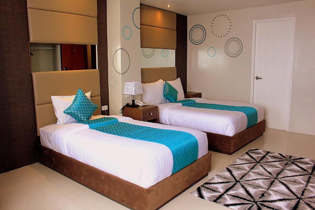 a hotel room with two beds with blue and white sheets at Hotel Estrella in Tacloban