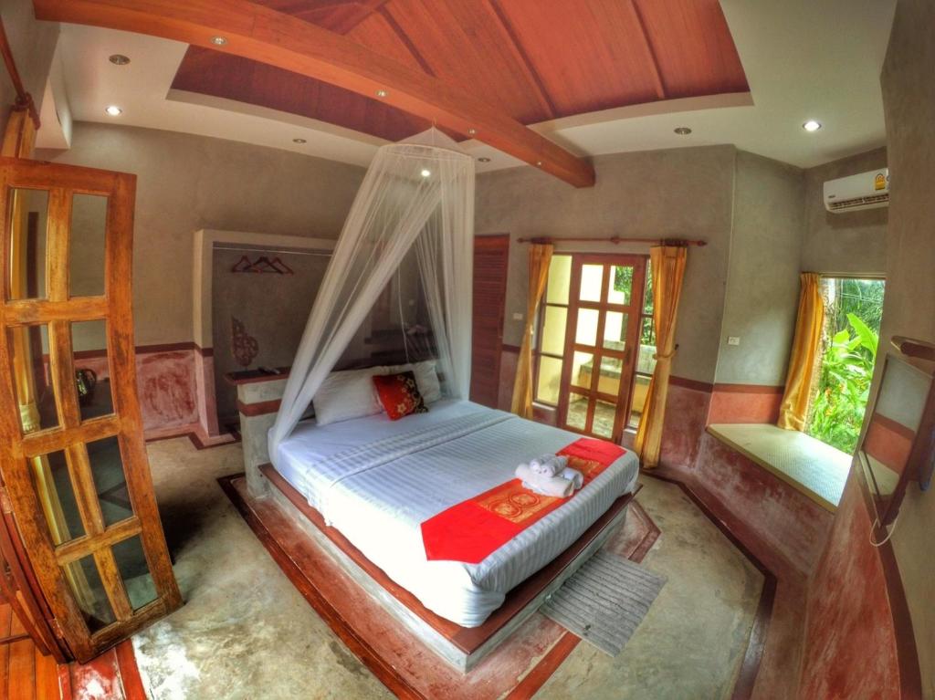 a bedroom with a bed with a mosquito net at Palms Hill Resort in Phangnga