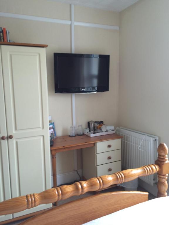 a bedroom with a bed with a television on the wall at Trelawney Guest House in Falmouth