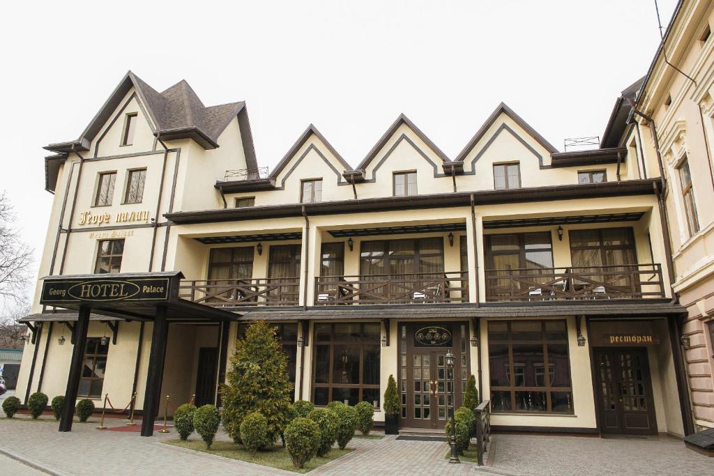 a large white building with balconies on a street at Georg Palace Hotel in Chernivtsi