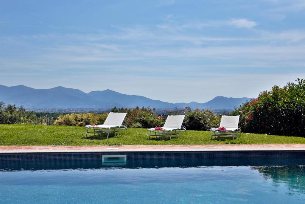 2 sillas y una piscina con montañas en el fondo en Bertolli Villas, en Matraia