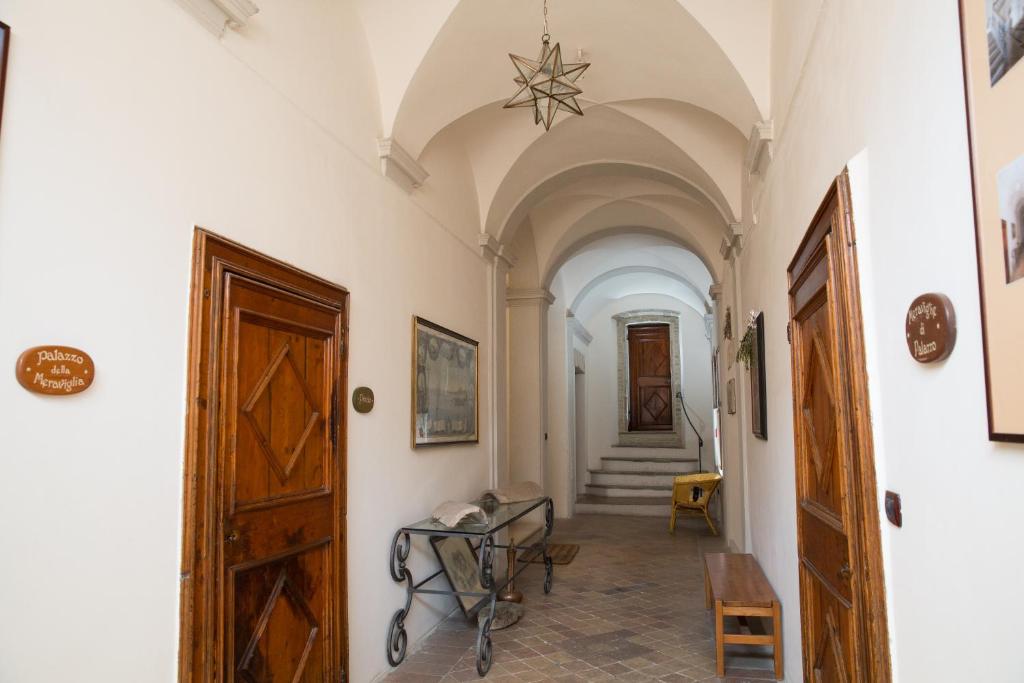 um corredor com paredes brancas e uma porta e escadas em Hotel Palazzo Meraviglia Albergo diffuso em Corinaldo