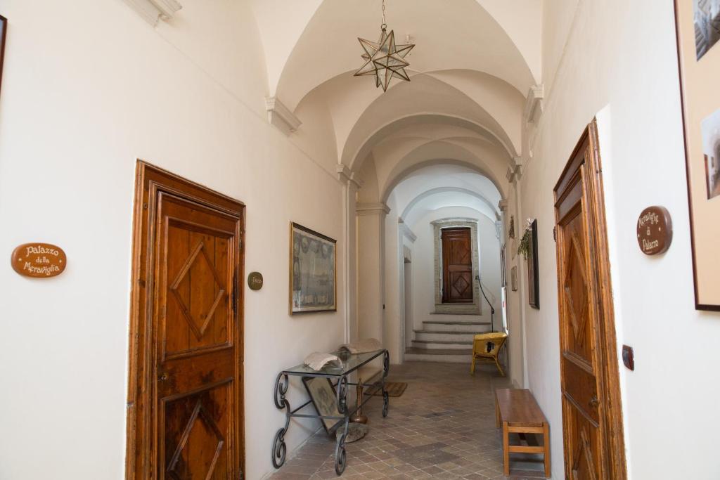 un pasillo con paredes blancas y una puerta y escaleras en Hotel Palazzo Meraviglia Albergo diffuso, en Corinaldo