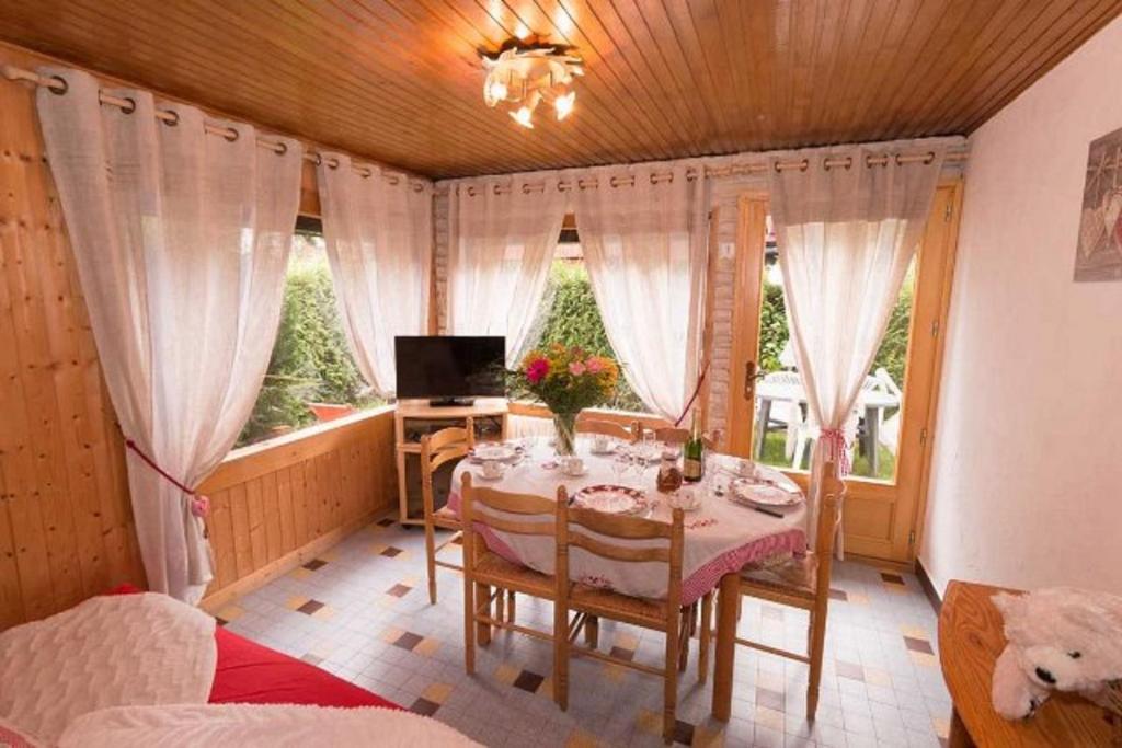 een eetkamer met een tafel in een kamer met ramen bij Le Petit Chalet in Morzine