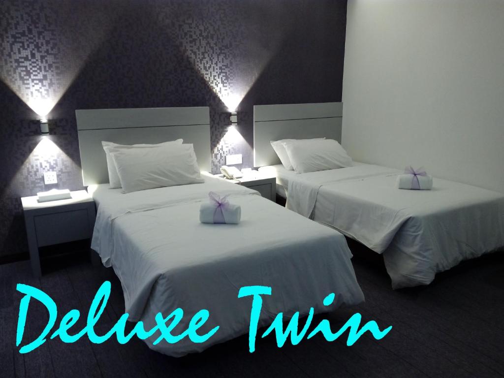 2 Betten in einem Hotelzimmer mit violetten Bogen in der Unterkunft Muar Traders Hotel in Muar