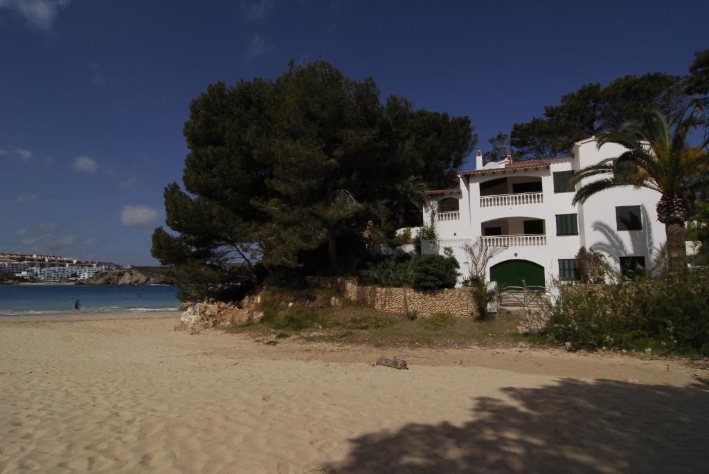 a white house on the beach next to the ocean at Apartamentos Jardin Playa in Punta Grossa