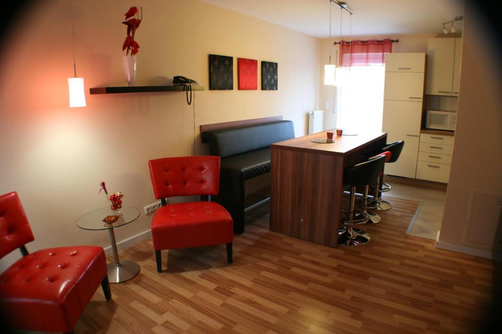 sala de estar con escritorio y sillas rojas en Ferienwohnung Weinberg, en Gründau