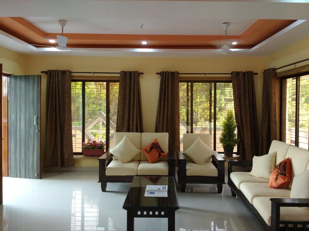 sala de estar con sofás, sillas y ventanas en Jeevan Geet, en Alibaug