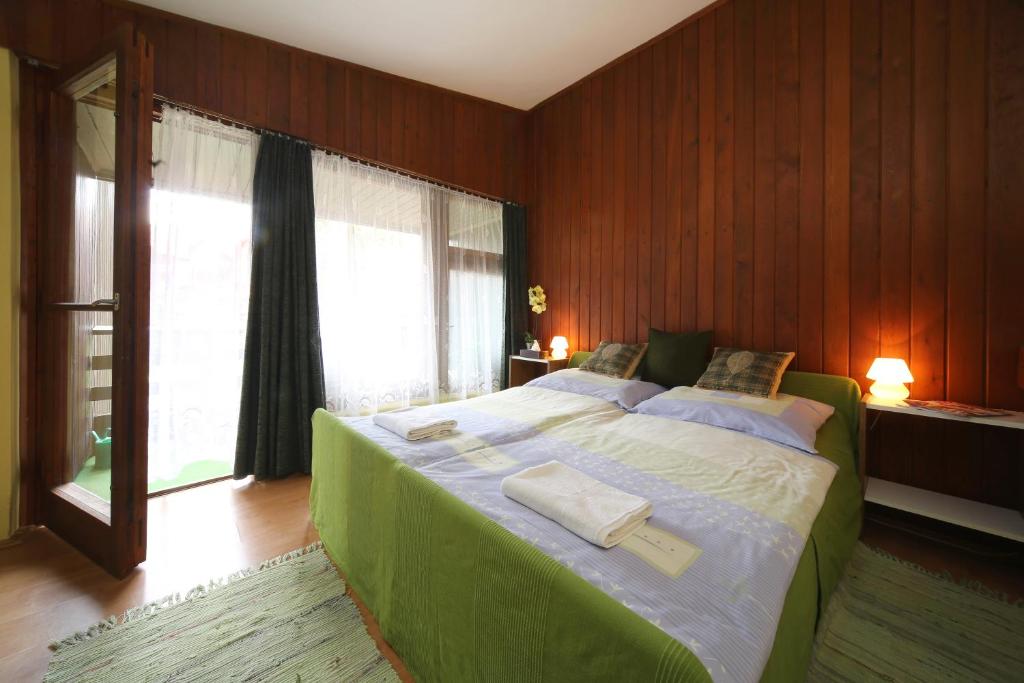 Schlafzimmer mit einem großen grünen Bett und einem Fenster in der Unterkunft Hotel Melis in Balatonlelle