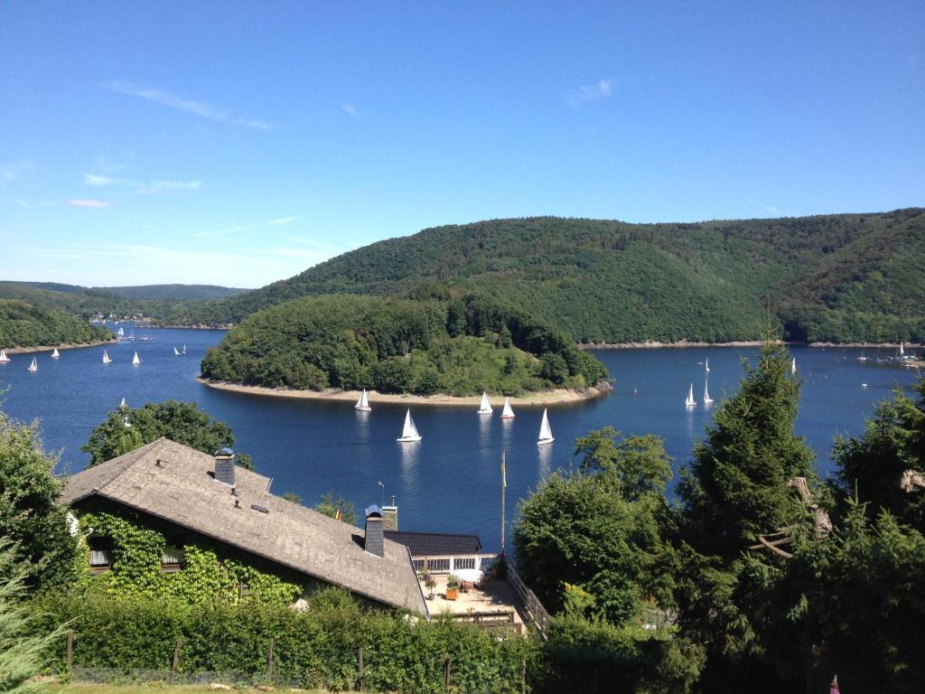 een uitzicht op een meer met zeilboten en een huis bij See-Oase Rurberg in Rurberg