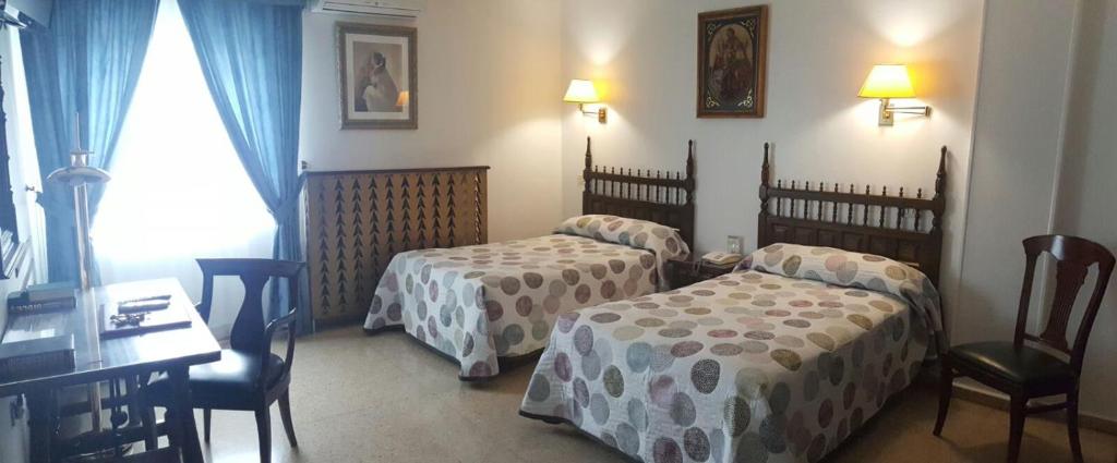 a hotel room with two beds and a table and chairs at Hotel Nico in Medinaceli