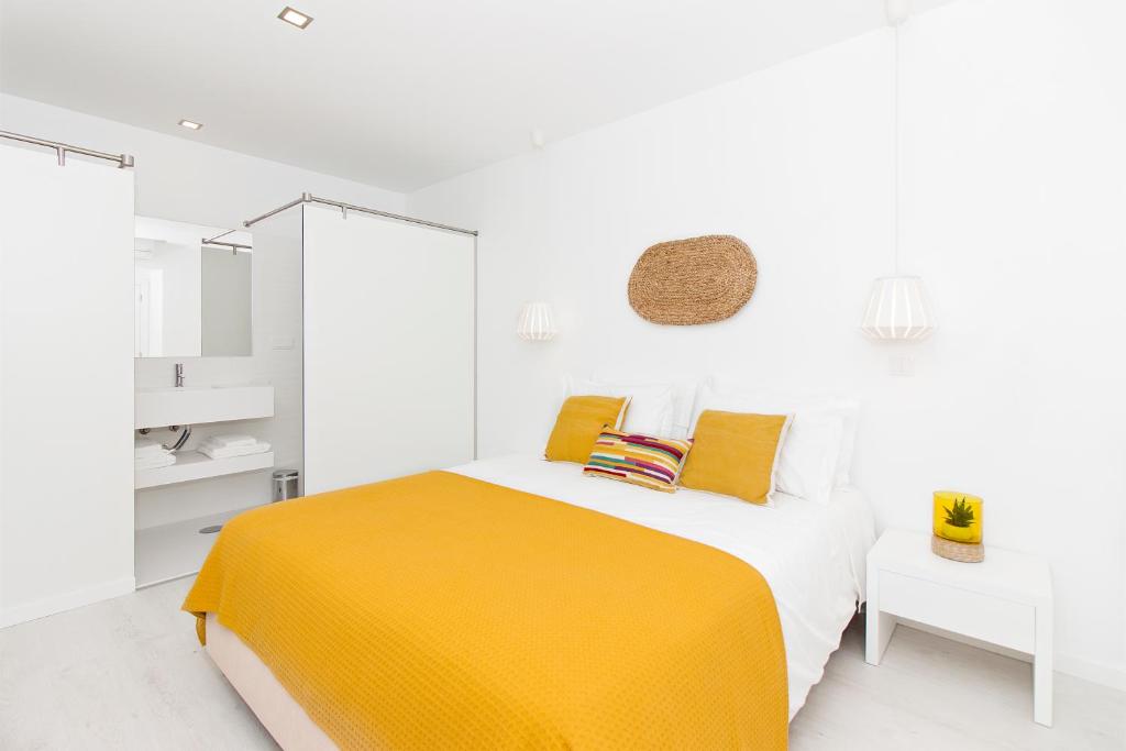 a white bedroom with a yellow bed and white cabinets at Villa Maça House in Sintra
